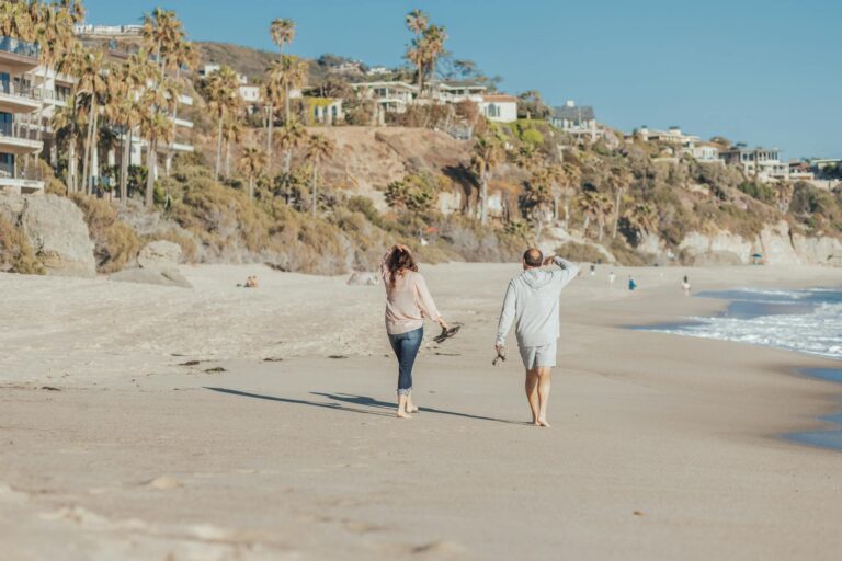 Mature couple walking along a sunny beach enjoying the ocean breeze and scenic view.