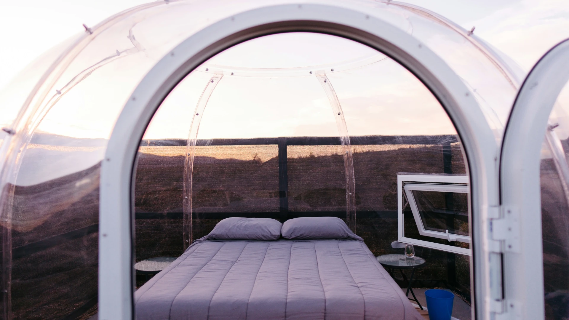 Ein Bett unter einer Plexiglaskuppel an einem Strand.