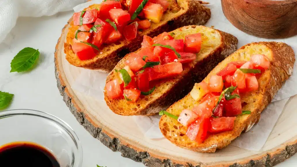 Auf einem Holzbrett liegen mehrere Bruschette.
