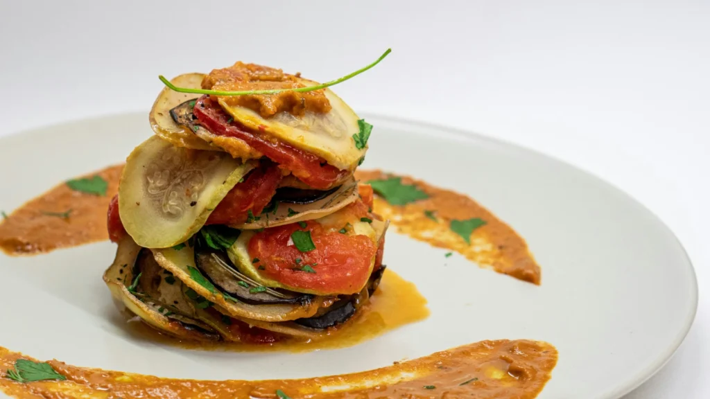 Auf einem weißen Teller ist eine Portion Ratatouille kunstvoll angerichtet.